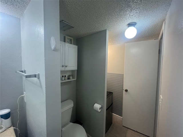 bathroom featuring a textured ceiling, toilet, and tile patterned floors