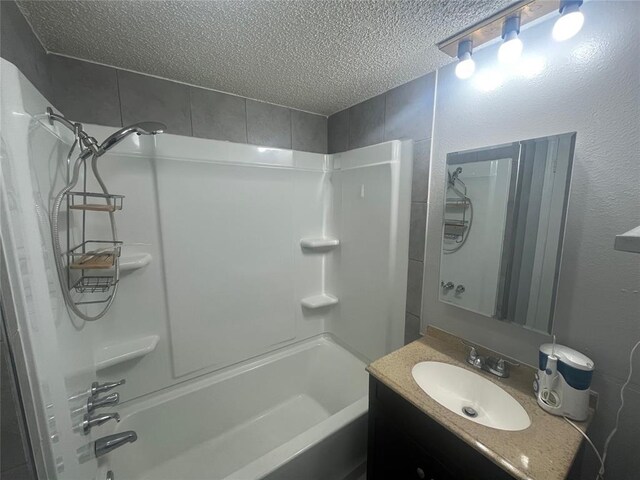 bathroom featuring a textured ceiling,  shower combination, and vanity