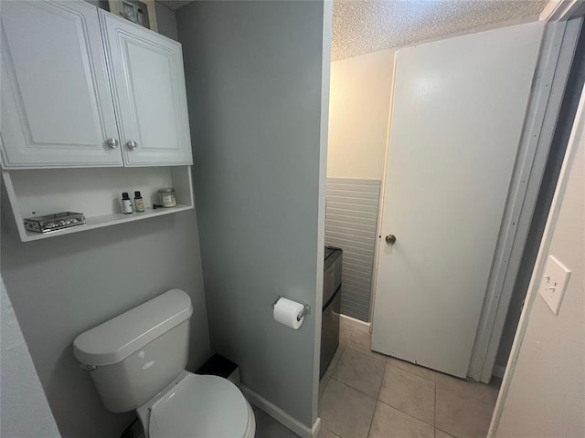 bathroom featuring toilet, tile patterned floors, and a textured ceiling