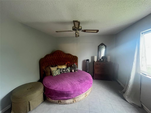 bedroom featuring ceiling fan, a textured ceiling, and light tile patterned floors