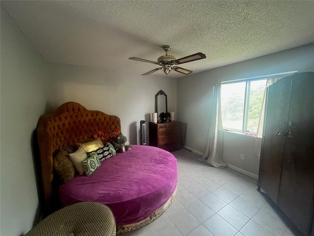 bedroom featuring light tile patterned floors, baseboards, a textured ceiling, and a ceiling fan