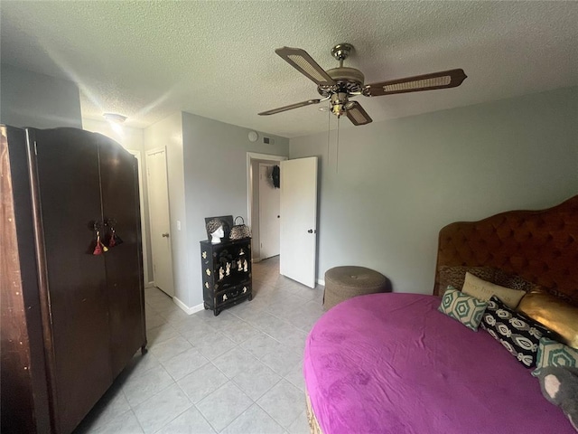 bedroom with light tile patterned floors, refrigerator, a textured ceiling, a ceiling fan, and baseboards
