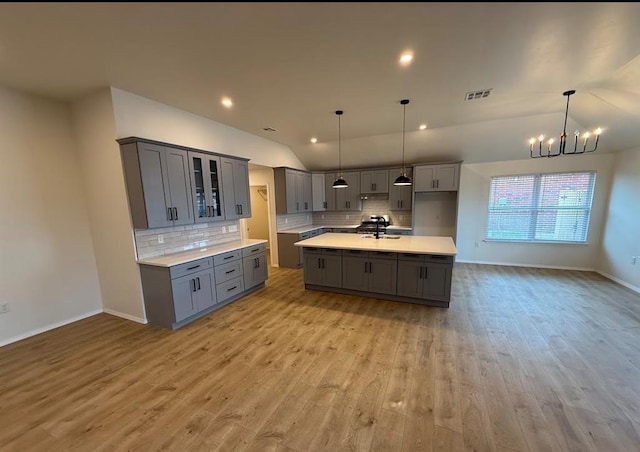 5000 SE 85th St, Oklahoma City, OK 73135 - kitchen featuring gray cabinets, vaulted ceiling, light wood-type flooring, tasteful backsplash, and a chandelier