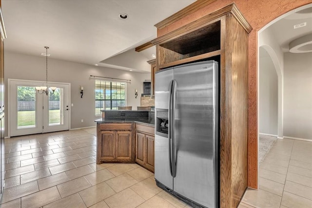 2900 Coventry Manor Dr, Oklahoma City, OK 73128 - kitchen featuring stainless steel refrigerator with ice dispenser, light tile patterned floors, brown cabinets, dark countertops, and a peninsula