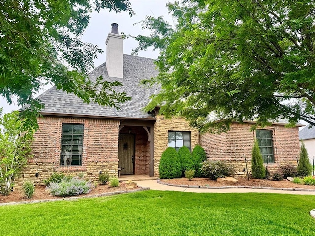 3209 NW 177th St, Edmond, OK 73012 - view of front of home with a front yard, a shingled roof, a chimney, stone siding, and brick siding