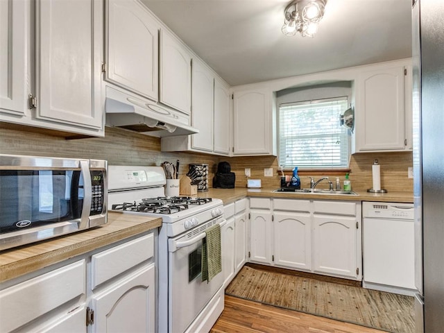 625 Jasmine Pl, Edmond, OK 73003 - kitchen with under cabinet range hood, stainless steel appliances, a sink, white cabinetry, and decorative backsplash