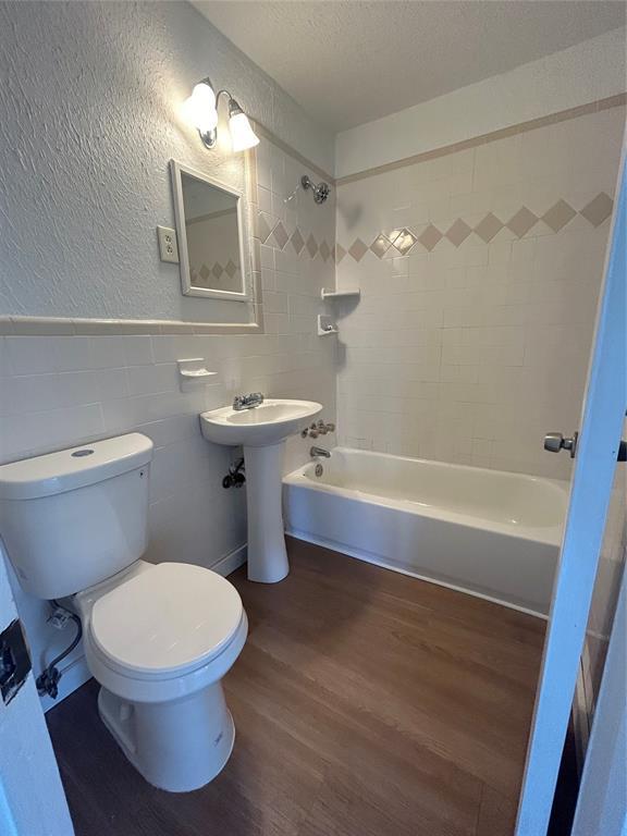 4404 N State St, Warr Acres, OK 73122 - bathroom featuring wood finished floors, tile walls, bathtub / shower combination, toilet, and a textured ceiling