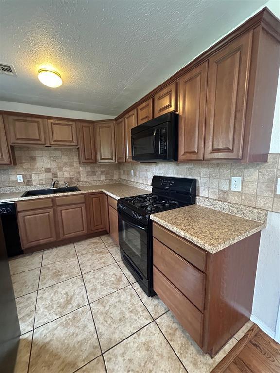 4404 N State St, Warr Acres, OK 73122 - kitchen featuring black appliances, a sink, tasteful backsplash, a textured ceiling, and brown cabinets