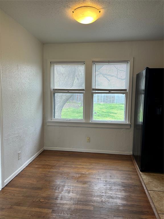 4404 N State St, Warr Acres, OK 73122 - unfurnished dining area with healthy amount of natural light, wood finished floors, baseboards, a textured ceiling, and a textured wall