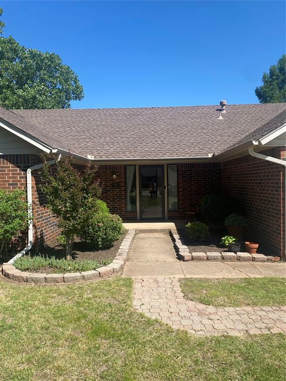 308 Jeffrey Laird Pl, Moore, OK 73160 - property entrance featuring brick siding, a shingled roof, and a yard
