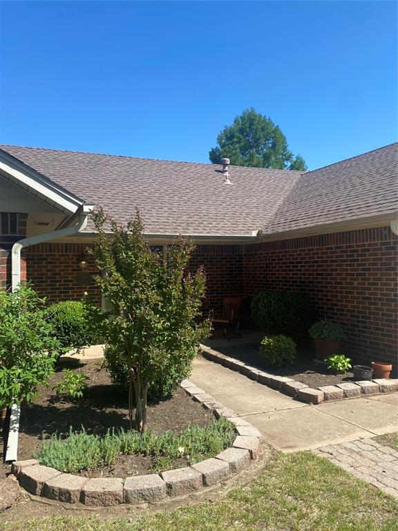 308 Jeffrey Laird Pl, Moore, OK 73160 - view of exterior entry featuring brick siding and roof with shingles