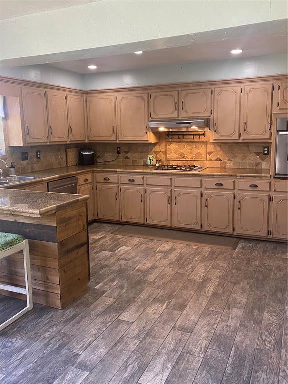 308 Jeffrey Laird Pl, Moore, OK 73160 - kitchen featuring under cabinet range hood, stainless steel appliances, dark wood-type flooring, backsplash, and recessed lighting