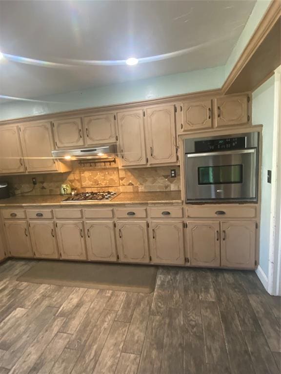 308 Jeffrey Laird Pl, Moore, OK 73160 - kitchen with appliances with stainless steel finishes, under cabinet range hood, dark wood-style floors, and backsplash