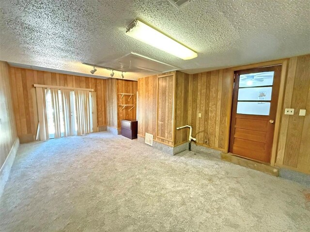 2405 S Mansfield St, Del City, OK 73115 - spare room featuring a textured ceiling, carpet, rail lighting, and wooden walls