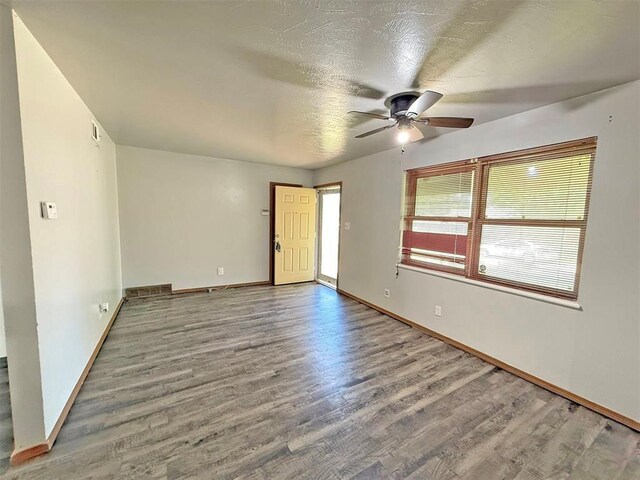 2405 S Mansfield St, Del City, OK 73115 - empty room with wood finished floors, a ceiling fan, baseboards, and a textured ceiling
