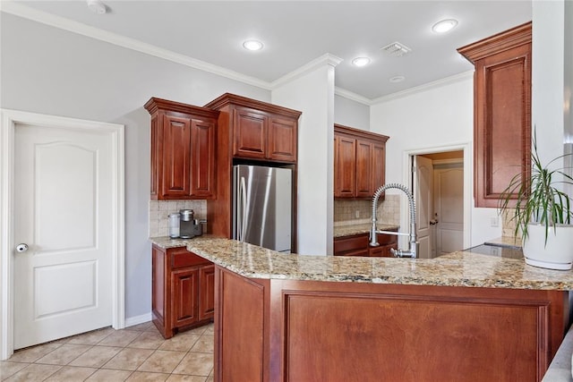 7713 Geneva Rea Ln, Yukon, OK 73099 - kitchen with freestanding refrigerator, decorative backsplash, ornamental molding, light stone countertops, and light tile patterned floors