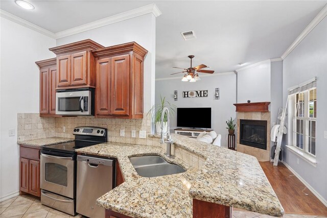 7713 Geneva Rea Ln, Yukon, OK 73099 - kitchen featuring appliances with stainless steel finishes, a sink, tasteful backsplash, ceiling fan, and crown molding