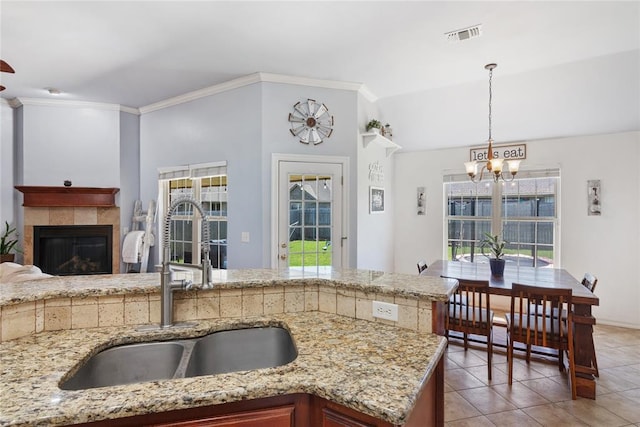 7713 Geneva Rea Ln, Yukon, OK 73099 - kitchen with a sink, a chandelier, healthy amount of natural light, light tile patterned floors, and crown molding