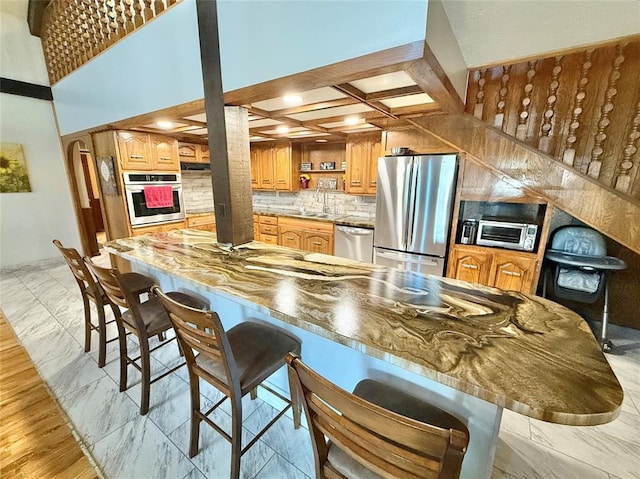 129 Park Dr, Sayre, OK 73662 - kitchen with stainless steel appliances, open shelves, coffered ceiling, a breakfast bar, and tasteful backsplash