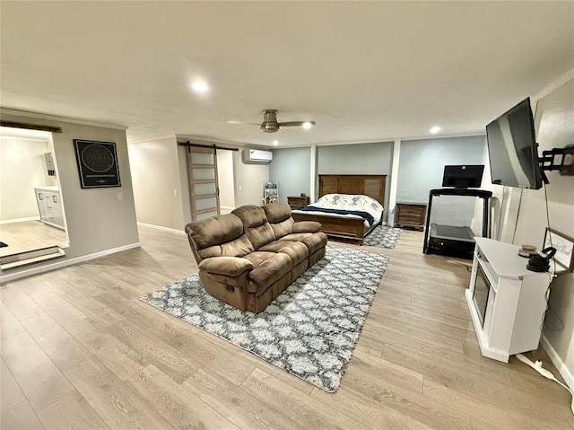 129 Park Dr, Sayre, OK 73662 - bedroom featuring a barn door, a wall mounted AC, light wood-style flooring, recessed lighting, and baseboards