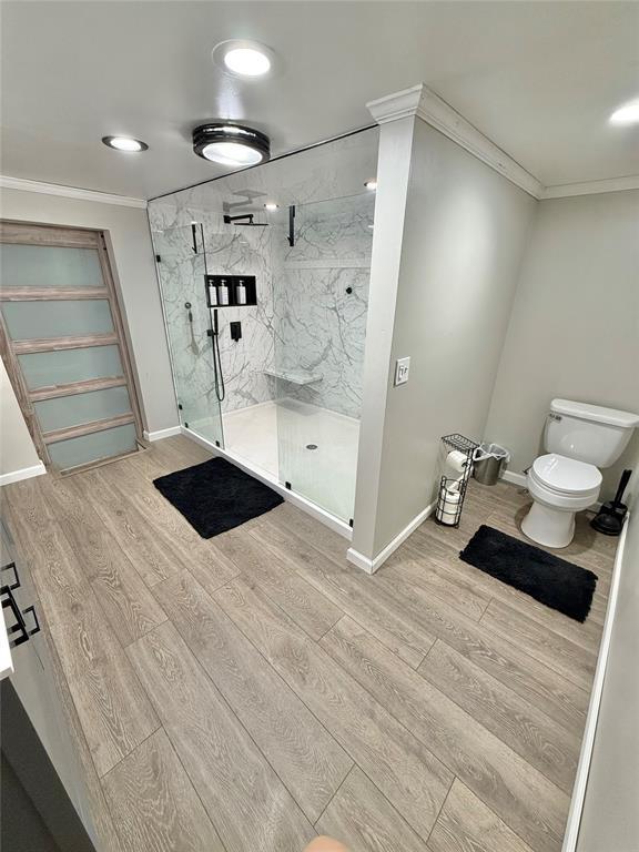 129 Park Dr, Sayre, OK 73662 - full bath featuring wood finished floors, crown molding, a marble finish shower, toilet, and baseboards