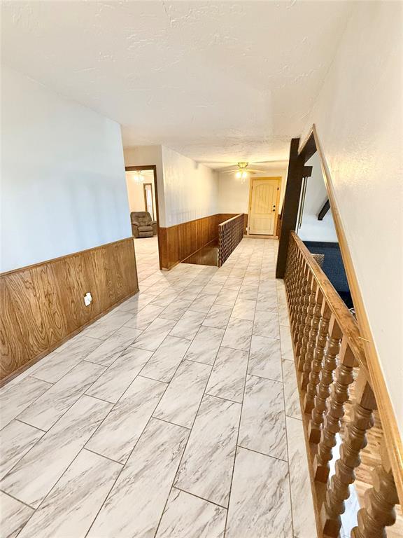 129 Park Dr, Sayre, OK 73662 - hall with a wainscoted wall, wood walls, and light marble finish flooring