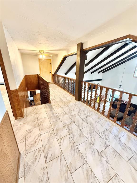 129 Park Dr, Sayre, OK 73662 - interior space featuring a ceiling fan, a wainscoted wall, marble finish flooring, and wooden walls