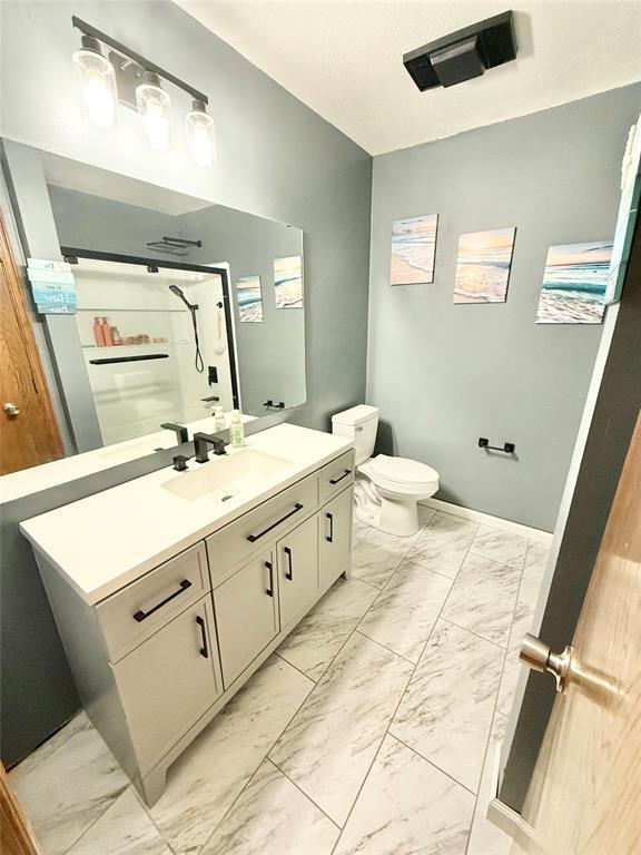 129 Park Dr, Sayre, OK 73662 - full bath with marble look tiles, vanity, toilet, and a stall shower