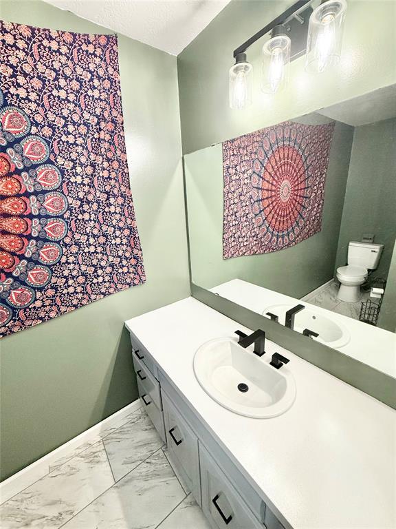 129 Park Dr, Sayre, OK 73662 - bathroom featuring marble finish floors, vanity, baseboards, and toilet