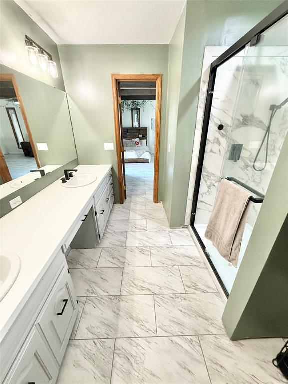 129 Park Dr, Sayre, OK 73662 - ensuite bathroom featuring double vanity, a marble finish shower, and marble look tile flooring