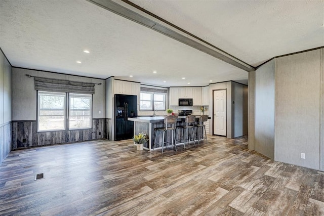 177074 Stephens Rd, Duncan, OK 73533 - kitchen featuring black appliances, wood finished floors, white cabinets, a textured ceiling, and a kitchen island