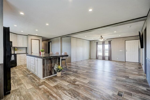 177074 Stephens Rd, Duncan, OK 73533 - kitchen with dark countertops, wood finished floors, white cabinets, a kitchen breakfast bar, and recessed lighting