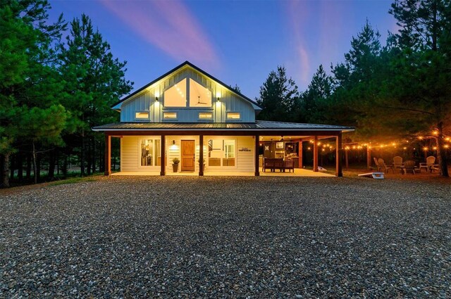 2690 Sweet Home Rd, Broken Bow, OK 74728 - rear view of house featuring board and batten siding, metal roof, gravel driveway, and covered porch
