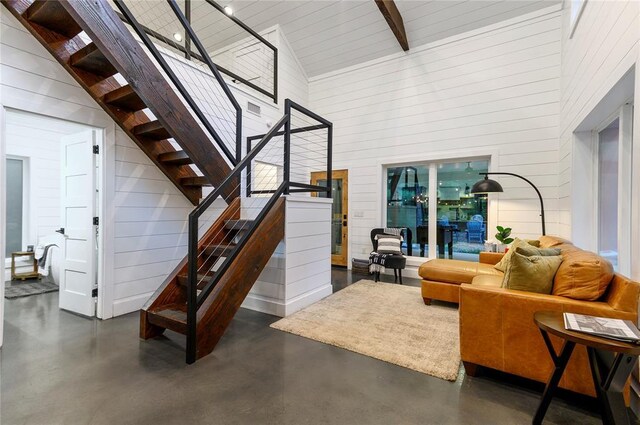 2690 Sweet Home Rd, Broken Bow, OK 74728 - living area featuring high vaulted ceiling, finished concrete floors, stairs, and wood walls