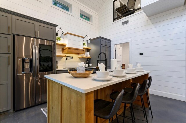 2690 Sweet Home Rd, Broken Bow, OK 74728 - kitchen featuring stainless steel refrigerator with ice dispenser, finished concrete floors, light countertops, a towering ceiling, and a kitchen island with sink