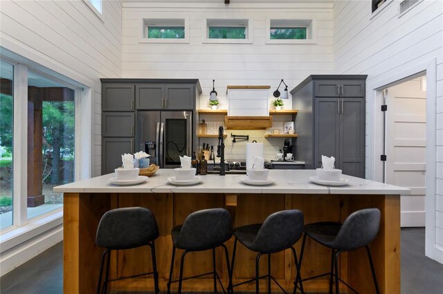 2690 Sweet Home Rd, Broken Bow, OK 74728 - kitchen with stainless steel fridge with ice dispenser, light countertops, finished concrete floors, open shelves, and wood walls