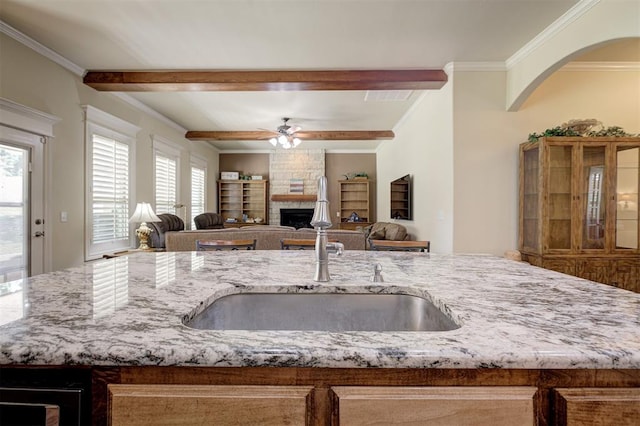 3327 Bobcat Trl, Guthrie, OK 73044 - kitchen with light stone counters, a large fireplace, a ceiling fan, open floor plan, and ornamental molding