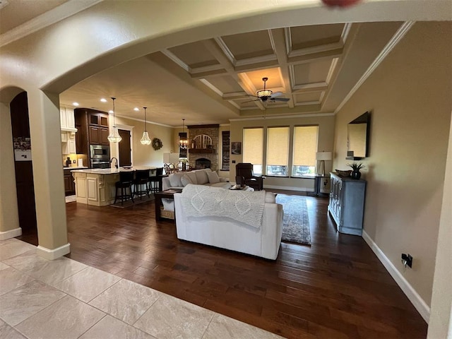 10921 SW 20th St, Yukon, OK 73099 - living room featuring arched walkways, ornamental molding, coffered ceiling, baseboards, and dark wood-style floors
