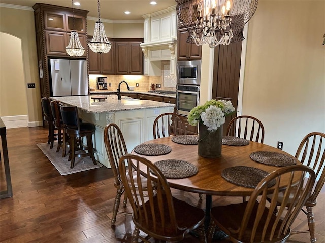 10921 SW 20th St, Yukon, OK 73099 - dining space featuring a chandelier, crown molding, recessed lighting, baseboards, and arched walkways