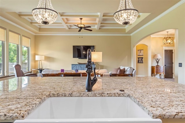 10921 SW 20th St, Yukon, OK 73099 - kitchen featuring open floor plan, a sink, ornamental molding, arched walkways, and light stone countertops