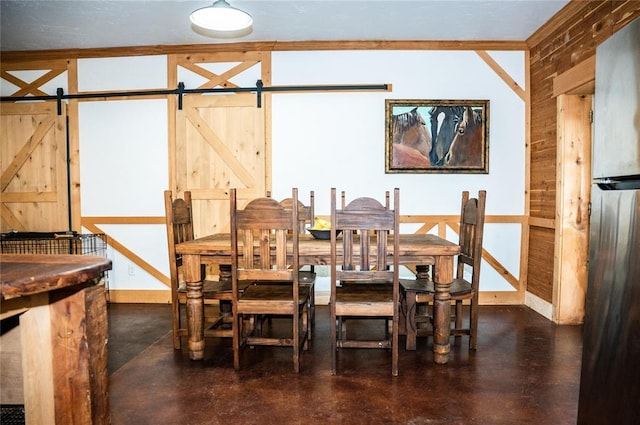 16301 Lewis Rd, Lexington, OK 73051 - dining space featuring a barn door, wood walls, concrete flooring, and baseboards