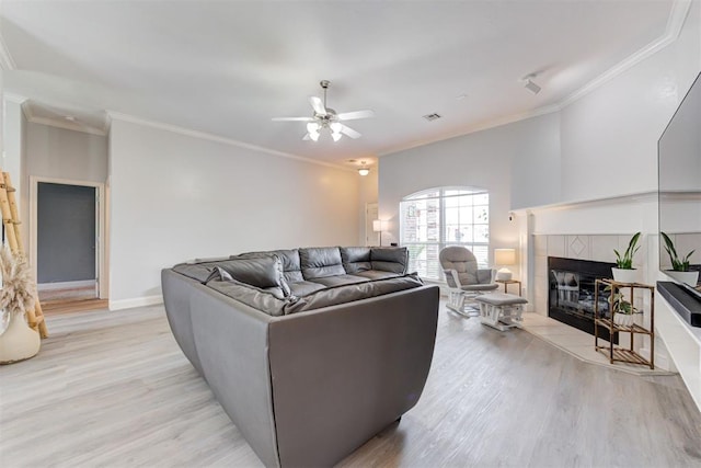 2333 Berry Ln, Midwest City, OK 73130 - living room with light wood-style flooring, ceiling fan, a tiled fireplace, crown molding, and baseboards