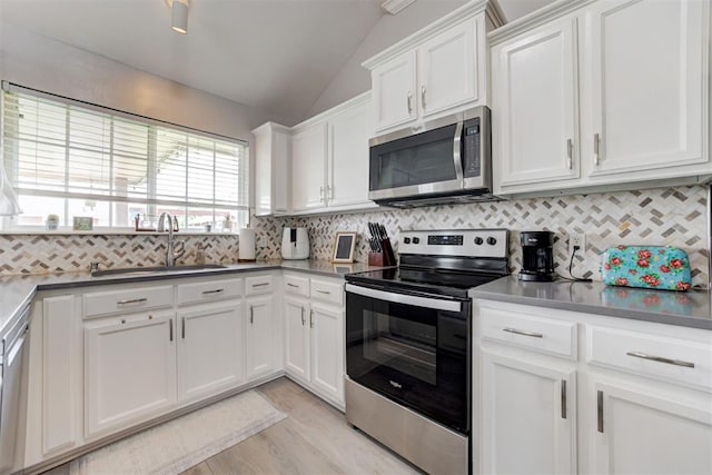 2333 Berry Ln, Midwest City, OK 73130 - kitchen with appliances with stainless steel finishes, a sink, vaulted ceiling, white cabinets, and light wood-style floors