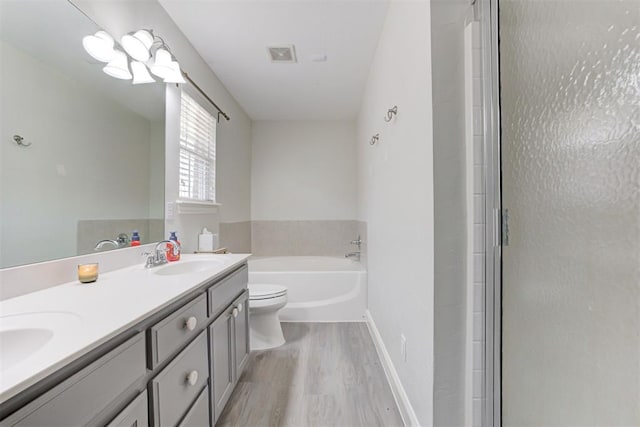 2333 Berry Ln, Midwest City, OK 73130 - full bath with wood finished floors, a garden tub, double vanity, toilet, and a shower