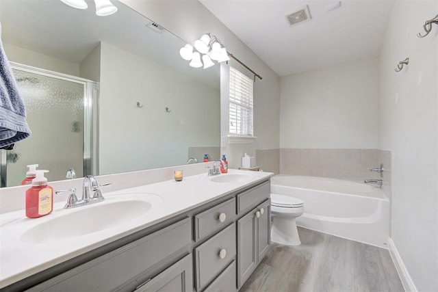2333 Berry Ln, Midwest City, OK 73130 - full bath with wood finished floors, double vanity, a garden tub, a shower stall, and toilet