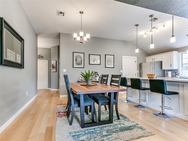 4409 Newport Dr, Norman, OK 73072 - dining area with vaulted ceiling, light wood-style flooring, a chandelier, baseboards, and rail lighting