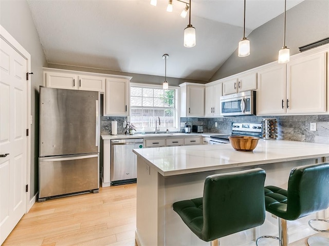 4409 Newport Dr, Norman, OK 73072 - kitchen with appliances with stainless steel finishes, light wood-style floors, vaulted ceiling, a peninsula, and light countertops