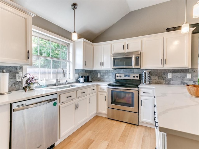 4409 Newport Dr, Norman, OK 73072 - kitchen with appliances with stainless steel finishes, a sink, light wood-style flooring, lofted ceiling, and white cabinets