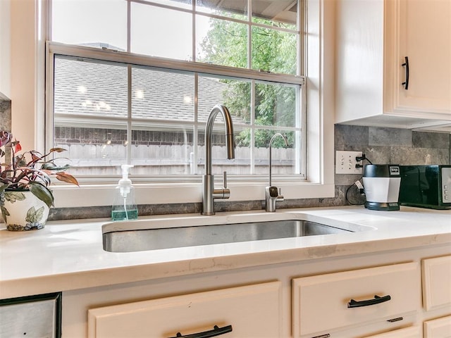 4409 Newport Dr, Norman, OK 73072 - kitchen featuring a sink, white cabinetry, and decorative backsplash