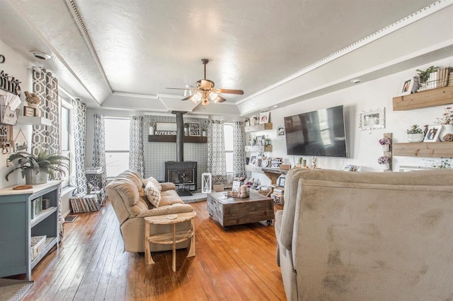 1505 N Piedmont Rd, Yukon, OK 73099 - living room with a raised ceiling, a wood stove, light wood-style flooring, and a ceiling fan